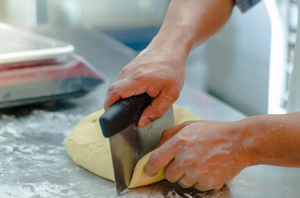 Mani di panettieri che lavorano e tagliano l'impasto del pane sulla superficie metallica con la farina distribuita — Foto Stock