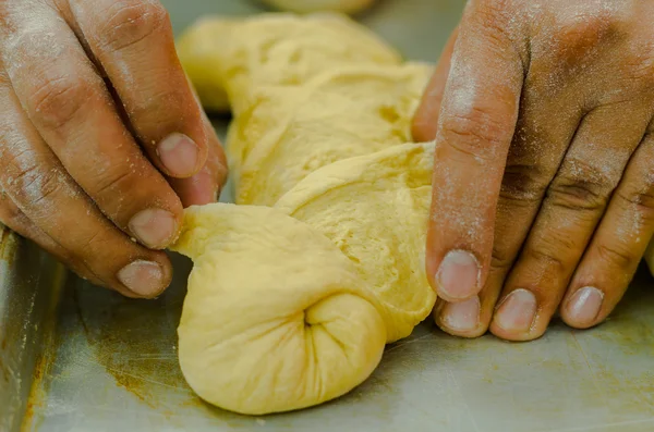 Le mani di panettieri che intrecciano la pasta di pane kringle prima di cottura — Foto Stock