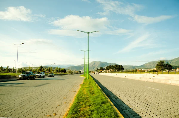 Grande paisagem do ponto de vista da estrada mostrando montanhas em distância, postes de lâmpada verde e céus azuis — Fotografia de Stock