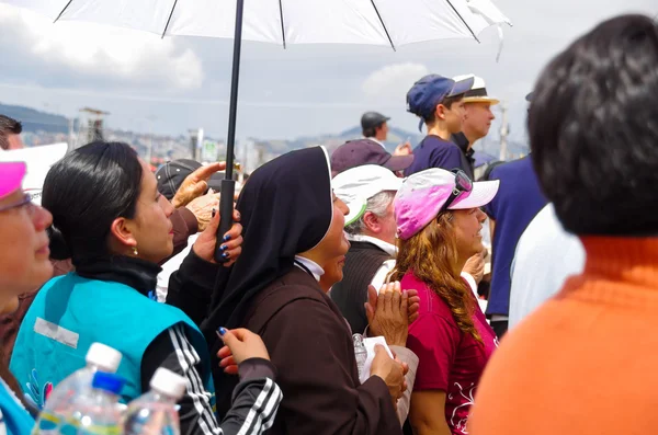 QUITO, ECUADOR - JULHO 7, 2015: No meio de mil pessoas uma freira está orando sob o sol, uma polícia está por trás dela — Fotografia de Stock