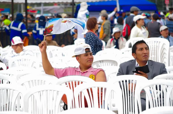 QUITO, ECUADOR - 7 LUGLIO 2015: Due uomini seduti su una sedia bianca in attesa di papa Francisco, asino, uno dei quali con una bandiera — Foto Stock