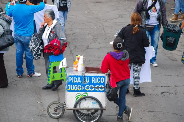 QUITO, ECUADOR - JULHO 7, 2015: Mulher de trás vendendo suco de coco, de pé no meio da rua — Fotografia de Stock