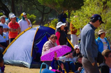 Quito, Ekvator - 7 Temmuz 2015: oturan ve Francisco kitle Ekvator çimenlerin üzerinde Papa'nın işitme insanlar. Arkadaki çadır
