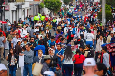 Quito, Ekvator - 7 Temmuz 2015: Bir sürü insan, yürüyüş izliyor ve insanları koruyan bir polis ile kalabalık cadde