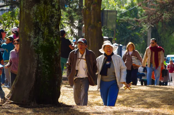 Quito, Ecuador - 7 juli 2015: Twee volwassenen met bescherming tegen de zon lopen door een park om te komen tot paus Francisco massa — Stockfoto