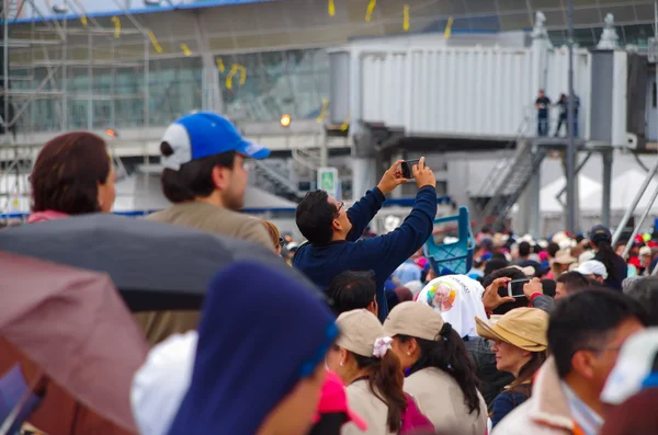 QUITO, ECUADOR - 7 DE JULIO DE 2015: En medio de un enorme grupo de personas, un hombre toma fotos con su teléfono móvil. Gente alrededor — Foto de Stock
