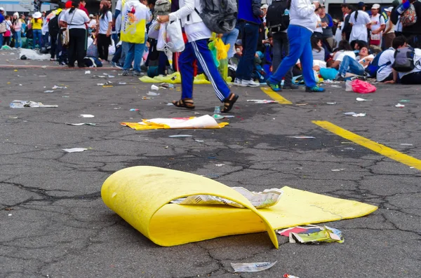 QUITO, ECUADOR - 7 DE JULIO DE 2015: Cartón amarillo en la calle, mucha basura después de un evento, gente detrás tratando de salir —  Fotos de Stock