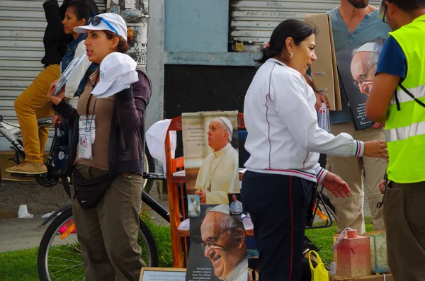 QUITO, ECUADOR - JULHO 7, 2015: Mulheres não identificadas vendendo cartazes do papa Francisco fora da missa, camisetas e chapéus — Fotografia de Stock
