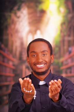 Katolik rahip geleneksel din adamı yaka gömlek giyen kamera bakan ayakta, tespih haç ile el ele tutarak, ileriye dönük, din kavramı