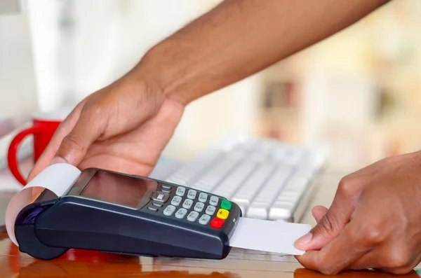 Closeup hands prcessing payment using credit card terminal device sitting on wooden surface — Stock Photo, Image