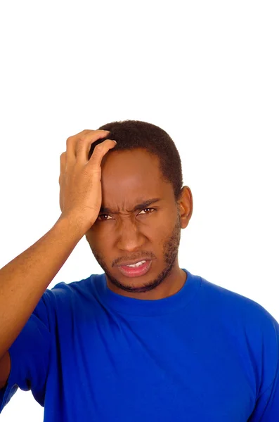 Headshot gestrest man dragen sterke blauw gekleurde t-shirt met behulp van handen aanraken van zijn eigen hoofd gefrustreerd, witte studio achtergrond — Stockfoto