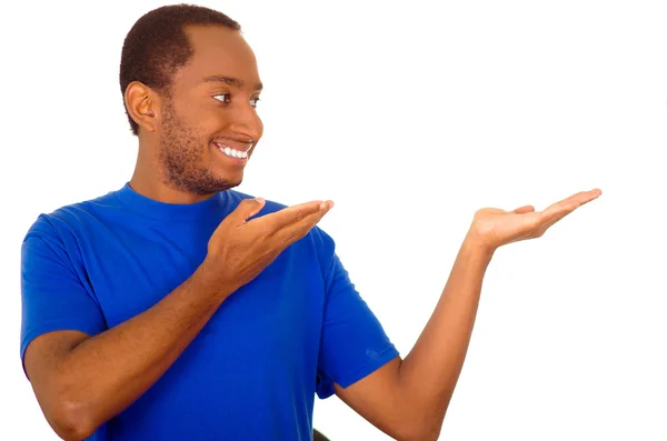 Hombre vistiendo una camiseta azul fuerte de pie e interactuando con las manos simulando la presentación mientras sonríe, fondo blanco del estudio —  Fotos de Stock