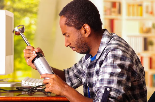 Człowiek siedzi przez biurko naprawy ręczny Blender za pomocą rąk, zdenerwowany i zirytowany wyraz twarzy podczas pracy — Zdjęcie stockowe