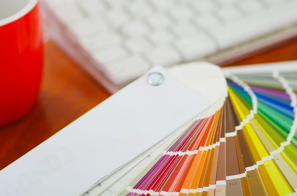 Close-up groot palet de verspreid in de voorkant van witte computer toetsenbord en rode koffie mok zittend op houten bureau, Designer concept — Stockfoto