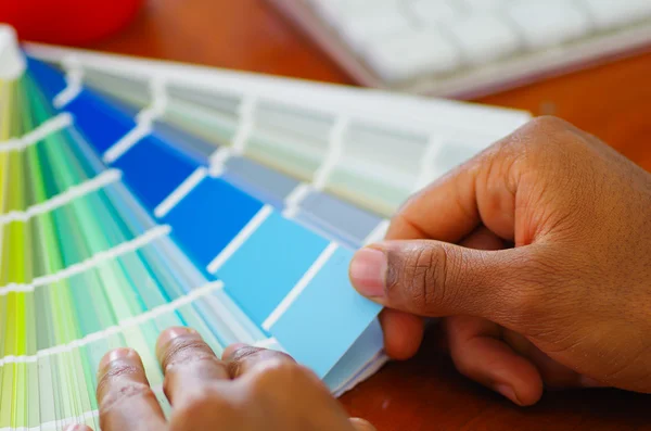 Primeros planos de las manos sosteniendo la paleta, mapa de colores desplegado frente al teclado de la computadora blanca, concepto de diseñador —  Fotos de Stock