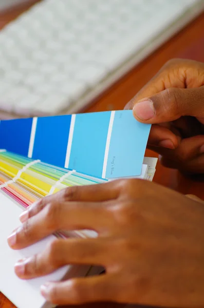 Primeros planos de las manos sosteniendo la paleta, mapa de colores desplegado frente al teclado de la computadora blanca, concepto de diseñador —  Fotos de Stock