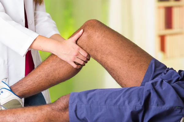 Man krijgt knie behandeling van Physio therapeut, haar handen houden van zijn been en het toepassen van Massage, letsel medische concept — Stockfoto