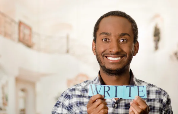 Headshot handsome man holding up small letters spelling the word write and smiling to camera