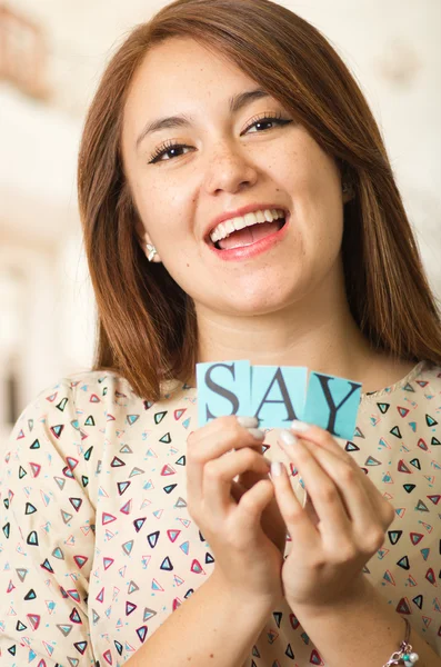 Headshot charmante brunette vrouw het houden van kleine letters spelling van het woord zeggen en glimlachend naar camera — Stockfoto