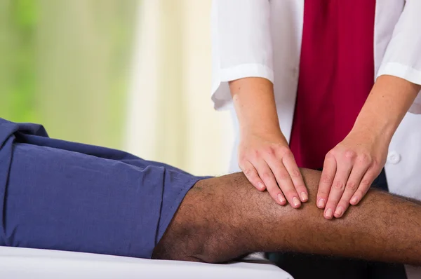 Мужчина получает физиотерапевт физиотерапевт лечение ног, ее руки работают на его телята применяя массаж, медицинская концепция — стоковое фото