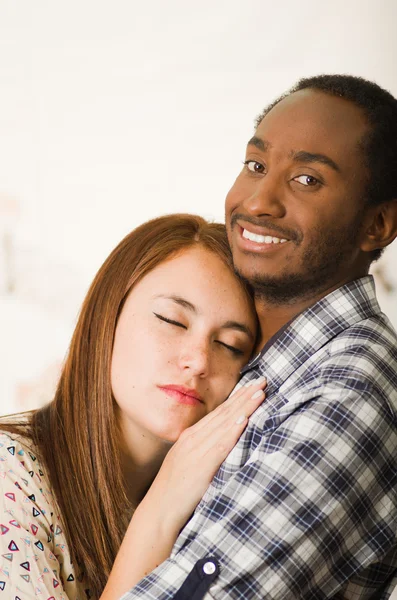 Interracial charmantes Paar in lässiger Kleidung posiert, während sie sich innig umarmt, sie hat geschlossene Augen und er lächelt, Profilwinkel mit weißem Studiohintergrund — Stockfoto