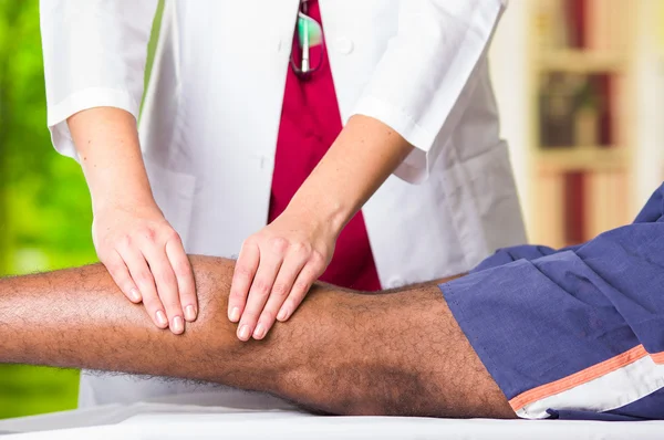 Mann bekommt physische Beinbehandlung von Physiotherapeut, ihre Hände arbeiten an seinen Waden Anwendung Massage, medizinisches Konzept — Stockfoto