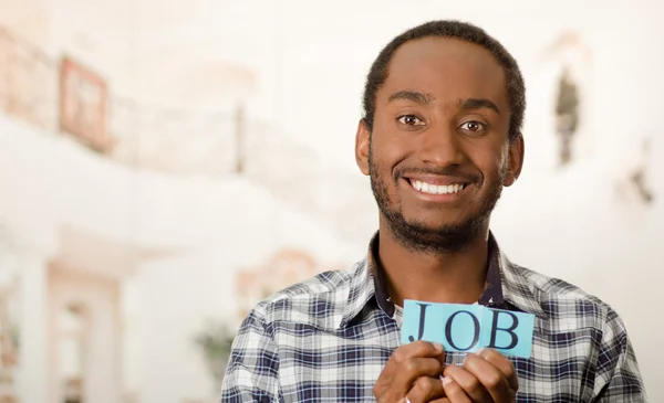 Cabeza guapo hombre sosteniendo pequeñas letras deletreando la palabra trabajo y sonriendo a la cámara — Foto de Stock