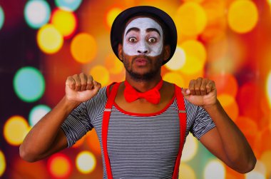 Pandomim adam yüz boya kamera komik ellerini, bulanık ışıklar arka plan kullanarak etkileşim için poz ile