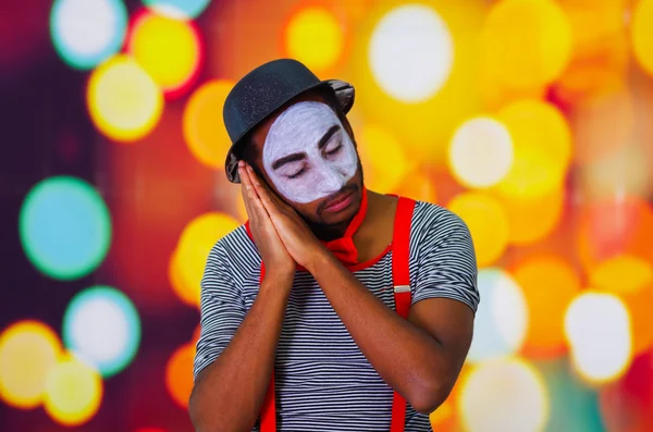 Headshot homme pantomime avec peinture faciale posant pour la caméra à l'aide de mains interagissant dormir, fond de lumières floues — Photo