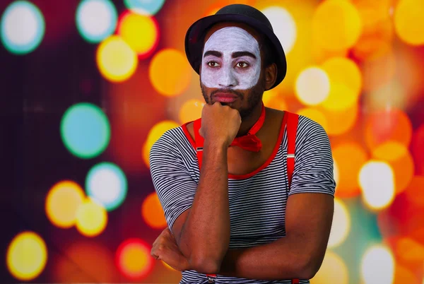 Pantomime homme portant de la peinture faciale posant pour caméra, en utilisant des mains interagissant langage corporel, arrière-plan de lumières floues — Photo