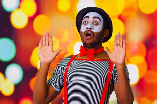 Headshot pantomima homem com pintura facial posando para câmera usando mãos interagindo, luzes embaçadas fundo — Fotografia de Stock