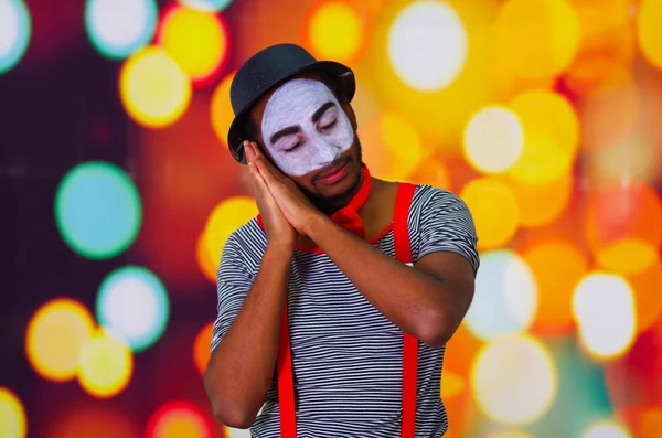 Headshot pantomima homem com pintura facial posando para câmera usando as mãos interagindo dormir, luzes embaçadas fundo — Fotografia de Stock