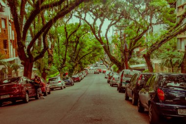 Porto Alegre, Brezilya - 06 Mayıs 2016: kaldırımlarda büyük ağaçlar, binaların dışında park edilmiş bir sürü araba ile güzel sokak