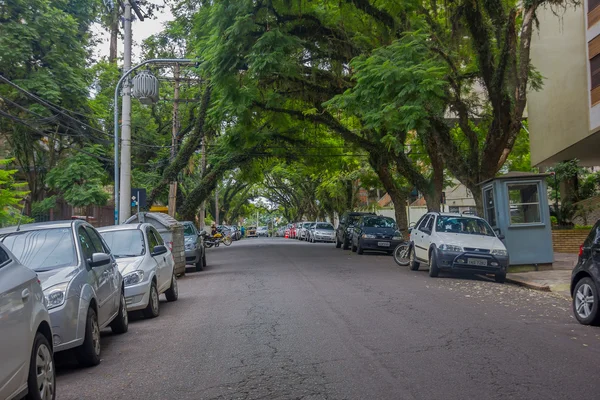 Порту-Алегрі, Бразилія-06 травня 2016: автомобілі, припарковані в стороні приємна вулиця з деревами в тротуарах — стокове фото