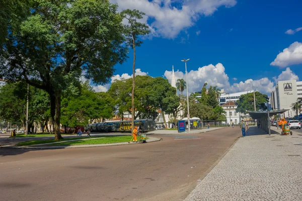 CURITIBA, BRASIL - 12 de mayo de 2016: peatones caminando por la estación de autobuses rodeados de grandes árboles — Foto de Stock