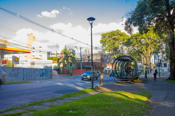 CURITIBA, BRASIL - 12 DE MAYO DE 2016: pasajeros esperando el autobús en la estación mientras algunos autos conducen por la calle —  Fotos de Stock