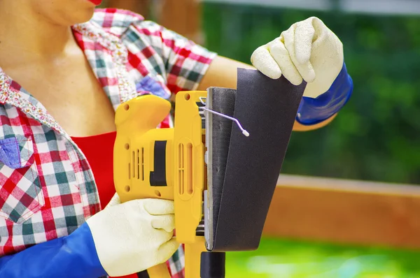 Worker woman removing the sandpaper from the electric sander — Stock Photo, Image