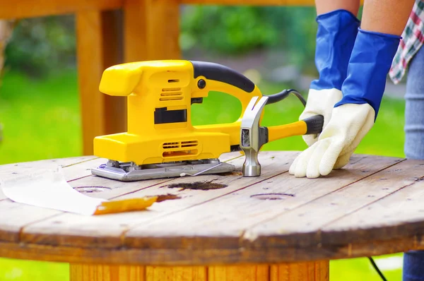 Electric sander over a table next to sanderpaper and a hammer — Stock Photo, Image