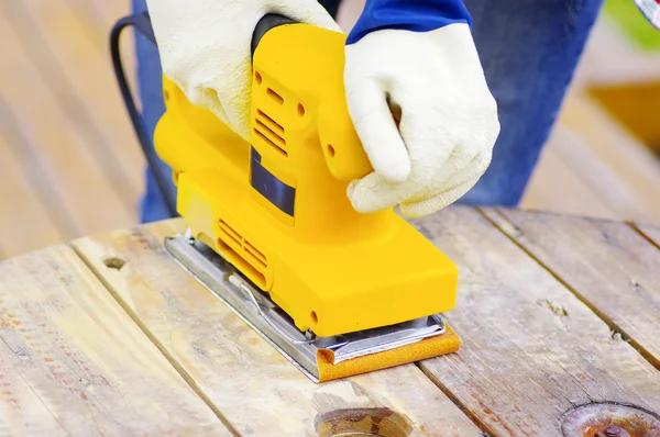 Gelber Elektroschleifer über einem Holztisch — Stockfoto