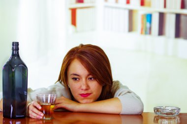 Resepsiyon yanındaki cam ve şişe, sarhoş depresif yüz ifadesi, alkollü kavramı üzerinde yalan sayaç Bar oturarak beyaz kazak giyen çekici kadın