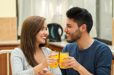 Genç çekici çift gözlük, meyve, meyve suyu ve kahve ile tezahürat kameraya gülümseyen kahvaltı masası tarafından oturmuş önünde, hostel çevre yerleştirilir