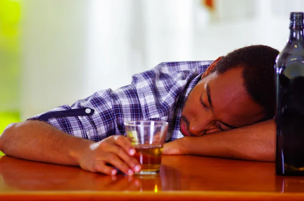 Όμορφος άνδρας φορώντας άσπρο πουκάμισο μπλε κάθεται γραμμή μετρητή που βρίσκεται πάνω από το γραφείο μεθυσμένος στον ύπνο, αλκοολούχα έννοια — Φωτογραφία Αρχείου