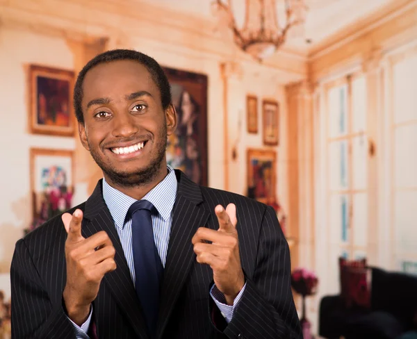 Bell'uomo vestito da uomo d'affari sorridente e che punta entrambe le dita indice alla macchina fotografica, sfondo lobbista — Foto Stock