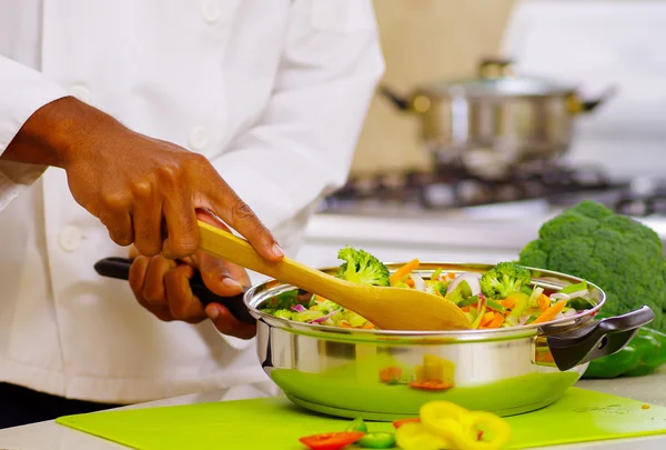 Detailní záběr rukou šéfkuchaře střídat barevné zeleniny v kovové pánvi, profesionální kuchyně, bílé pozadí — Stock fotografie