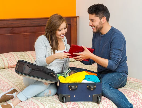 Unga charmiga spansktalande par casual kläder sitter på sängen packning till resväska tillsammans, hostel pensionat koncept — Stockfoto