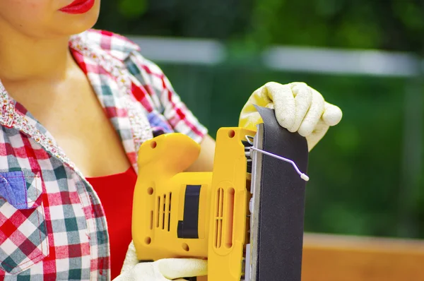 Mujer con guantes de trabajo quita el papel de lija de la lijadora eléctrica —  Fotos de Stock