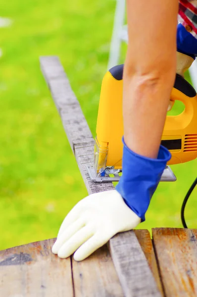 Yellow electric jigsaw cutting a piece of wood — Stock Photo, Image