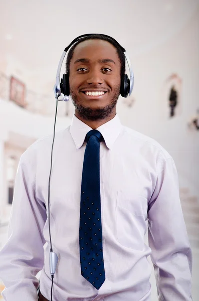 Beau homme portant des écouteurs avec microphone, chemise à rayures blanches et cravate, posant interagissant travailler pour la caméra — Photo