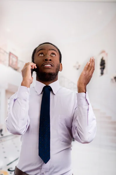 Handsome man wearing shirt and tie standing in lobby area talking on mobile phone, business concept — Stock Photo, Image