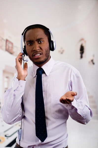 Handsome man wearing headphones with microphone, white striped shirt and tie, interacting slightly upset facial expression, business concept — Stock Photo, Image